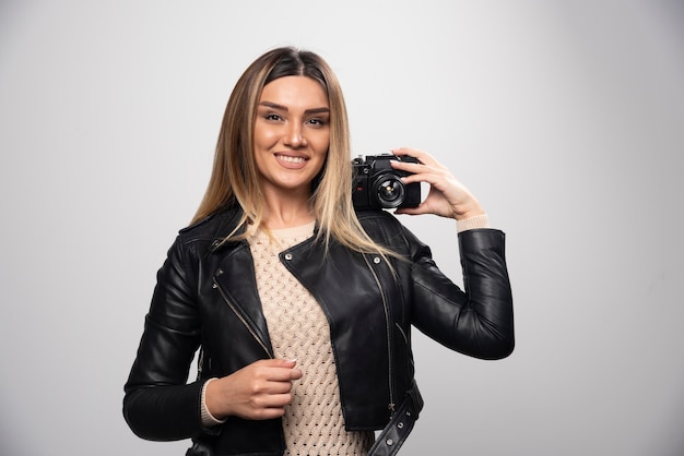 Menina com jaqueta de couro tirando fotos em posições elegantes e positivas