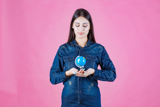 Menina com jaqueta jeans segurando um minibolho na palma da mão