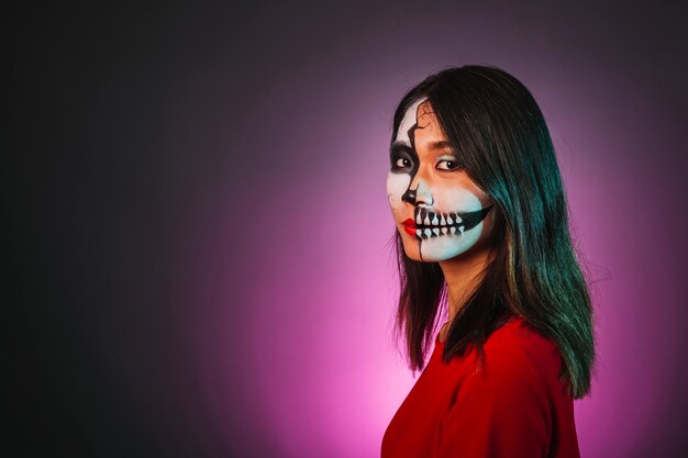 Menina com maquiagem e máscara de Halloween olhando para o lado oposto