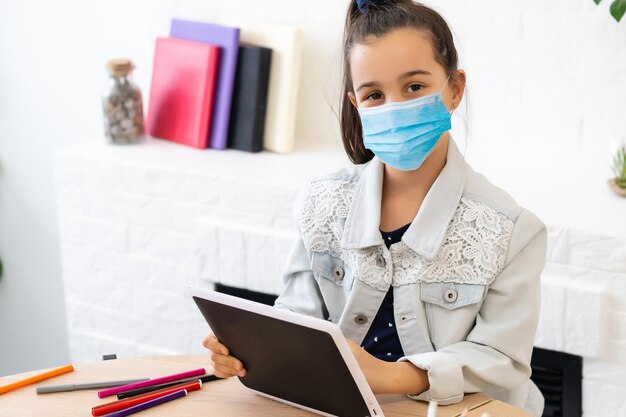 menina com máscara médica estudando em casa. epidemia, pandemia.