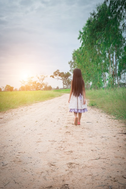 Menina com o cabelo longo que desgasta o vestido está andando longe do yo