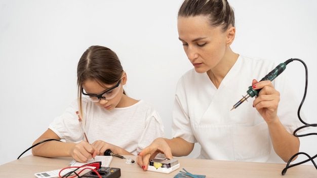 Menina com óculos de proteção e professora fazendo experiências científicas