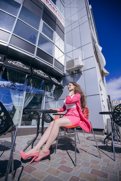Menina com óculos de sol sentado no terraço de um restaurante