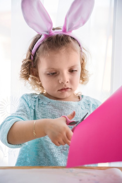 Foto grátis menina com orelhas de coelho cortando papel