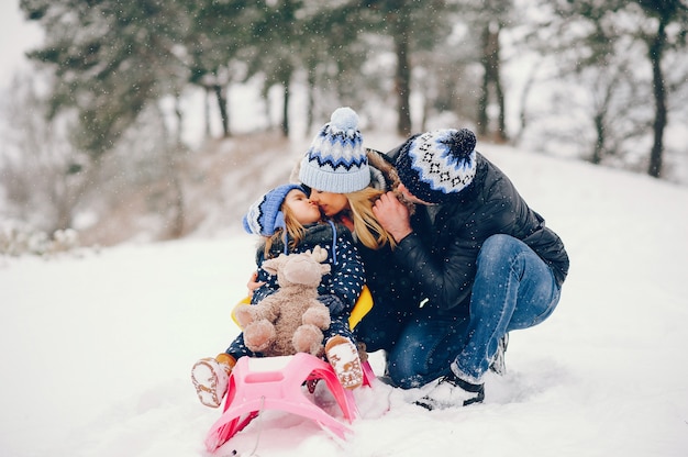 Menina com os pais brincando em um parque de inverno