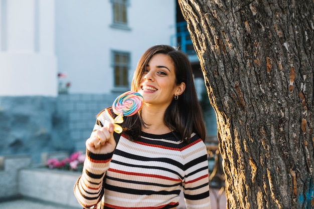 Foto grátis menina com pirulito colorido ao lado da árvore