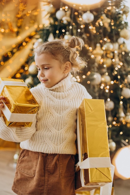 Menina com presentes de natal debaixo da árvore de natal