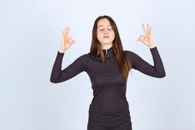 Menina com roupas pretas, fazendo meditação.