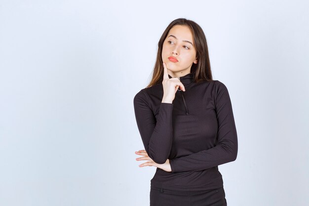 Menina com roupas pretas parece pensativa e duvidosa.