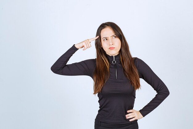 Menina com roupas pretas parece pensativa e duvidosa.