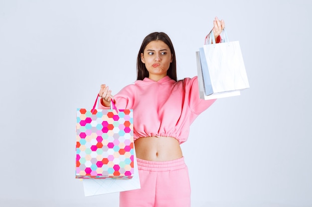 Menina com sacolas de compras coloridas parece insatisfeita.