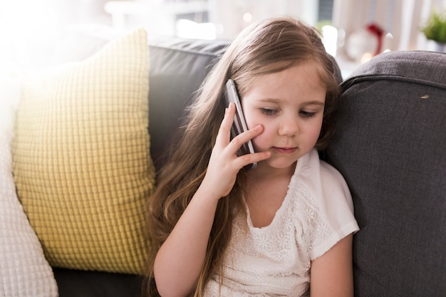 Menina com smartphone no sofá