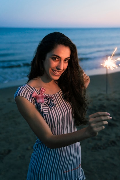 Menina com sparkler em uma praia do por do sol