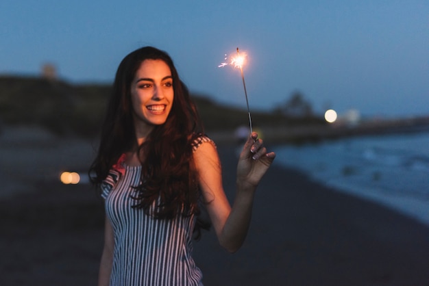 Menina com sparkler na praia