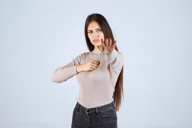 Menina com suéter cinza dando poses desagradáveis e sedutoras.