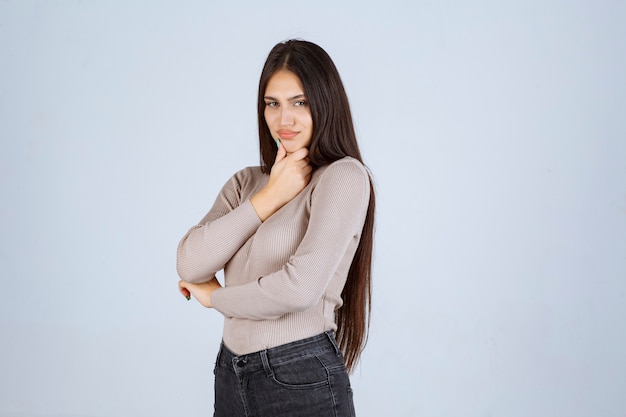 Menina com suéter cinza dando poses desagradáveis e sedutoras.