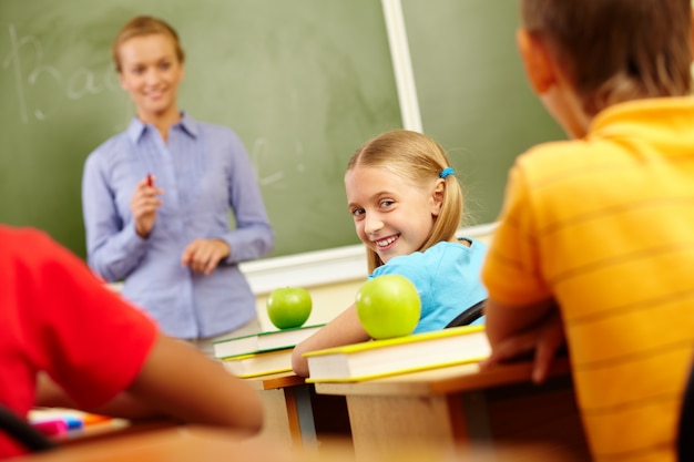 Menina com t-shirt azul que sorri na sala de aula