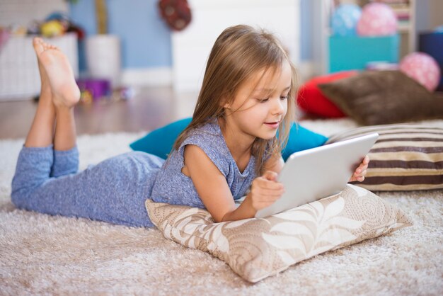 Menina com tablet digital no tapete