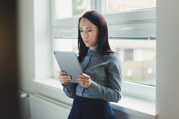 Menina com tablet perto da janela