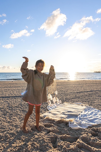 Foto grátis menina com um apanhador de sonhos à beira-mar ao pôr do sol