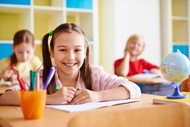 Menina com um grande sorriso em uma sala de aula
