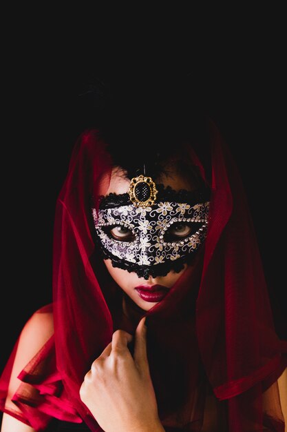 Menina com um lenço vermelho na cabeça e uma máscara veneziana