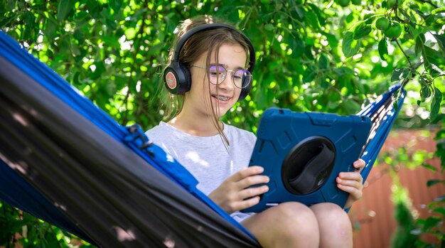 Foto grátis menina com um tablet em uma rede no jardim