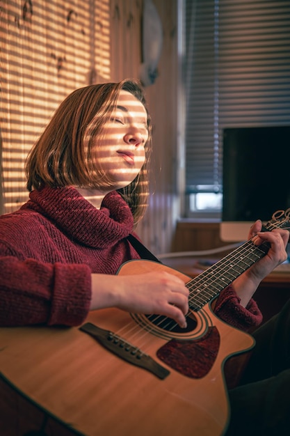 Menina com um violão sob o sol através das cortinas