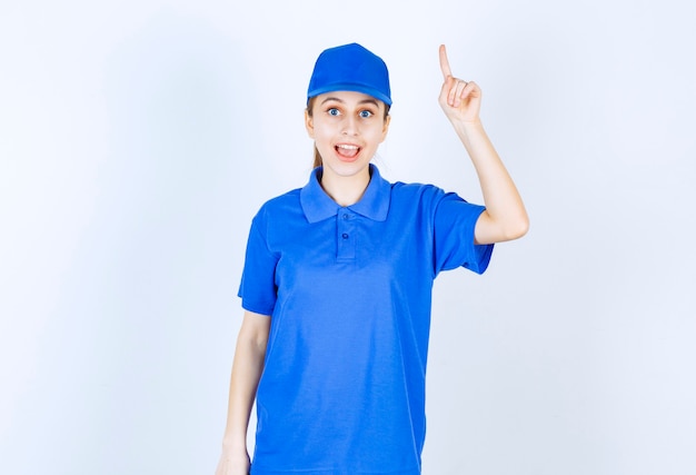 Foto grátis menina com uniforme azul, apontando para algo acima.