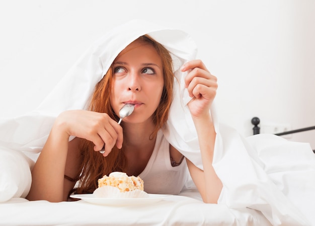 Menina comendo biscoito na cama