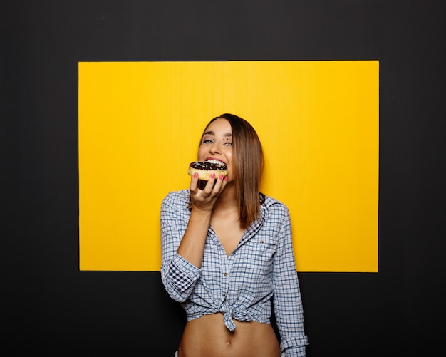 Menina comendo rosquinha com cobertura de chocolate