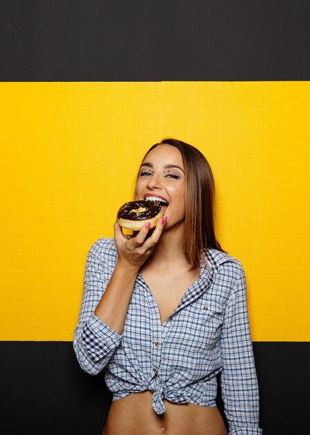 Menina comendo rosquinha com cobertura de chocolate