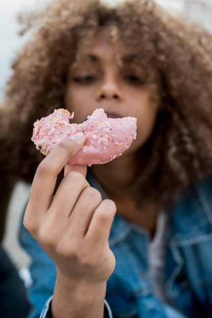 Menina comendo rosquinha rosa