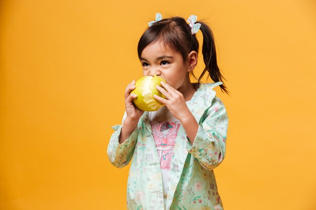 Menina criança comendo maçã.