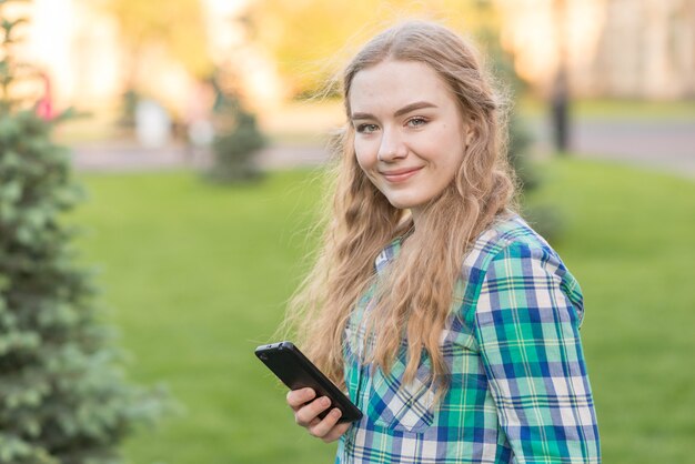 Menina da escola com o smartphone no parque