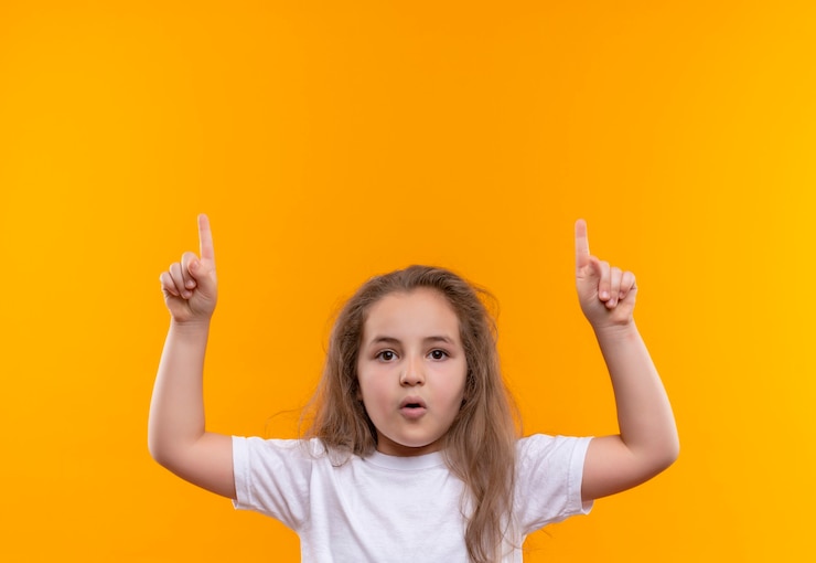 Foto grátis menina da escola vestindo camiseta branca levanta o dedo na parede laranja isolada