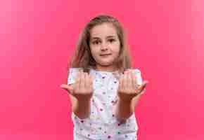 Foto grátis menina da escola vestindo camiseta branca mostrando o tamanho na parede rosa isolada