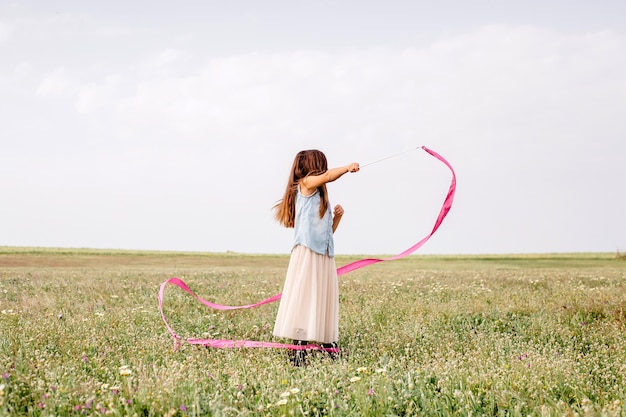 Menina dançando com fita ginástica no campo