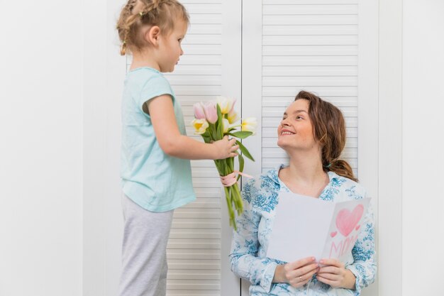 Menina dando buquê de flores para a mãe no dia das mães