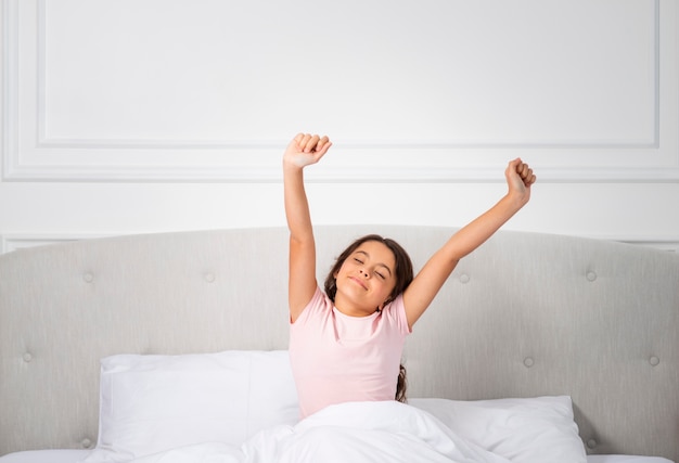 Foto grátis menina de alto ângulo na cama acordando