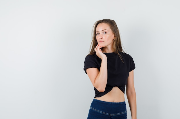 Menina de blusa preta, calça tocando o queixo e linda