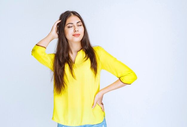 Menina de camisa amarela parece cansada ou tem dor de cabeça.