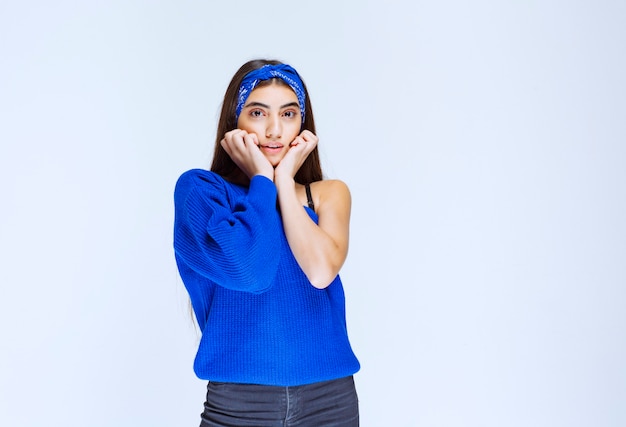 Menina de camisa azul pensando e analisando.