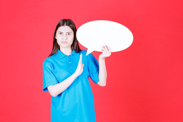 Menina de camisa azul segurando um quadro oval de informações e parando alguma coisa