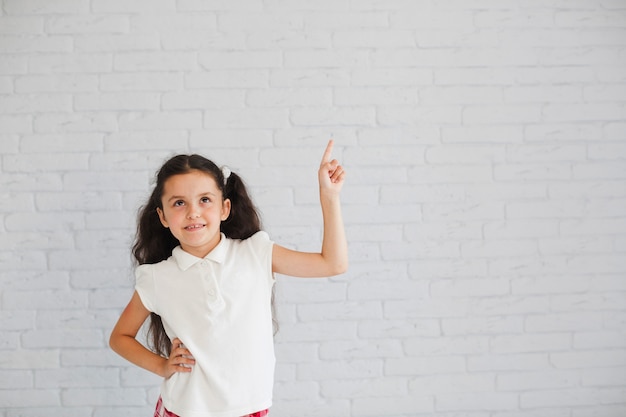 Menina de camisa branca apontando para cima