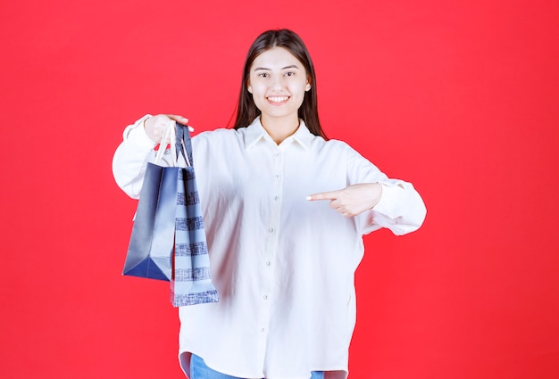 Menina de camisa branca segurando várias sacolas de compras