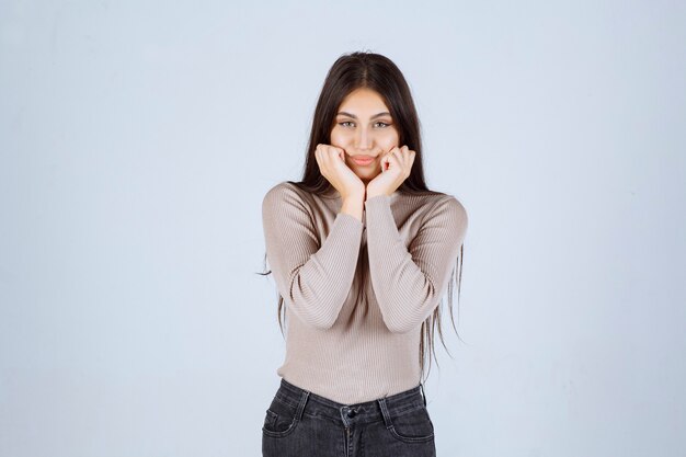 Menina de camisa cinza dando poses convidativas e sedutoras.