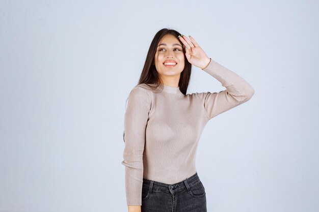 Menina de camisa cinza dando poses positivas e atraentes.