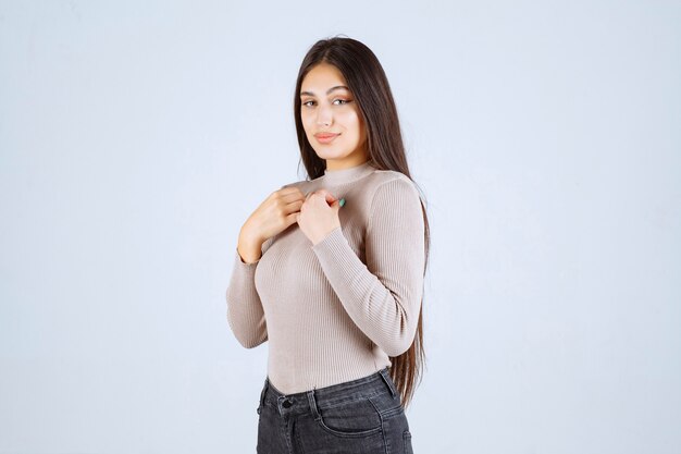 Menina de camisa cinza dando poses positivas e atraentes.