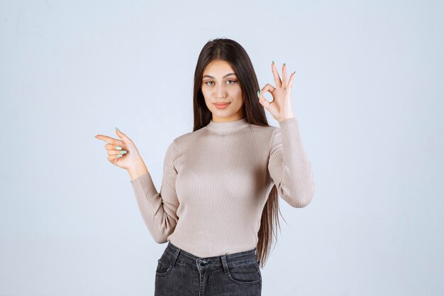 Menina de camisa cinza, desfrutando de algo.